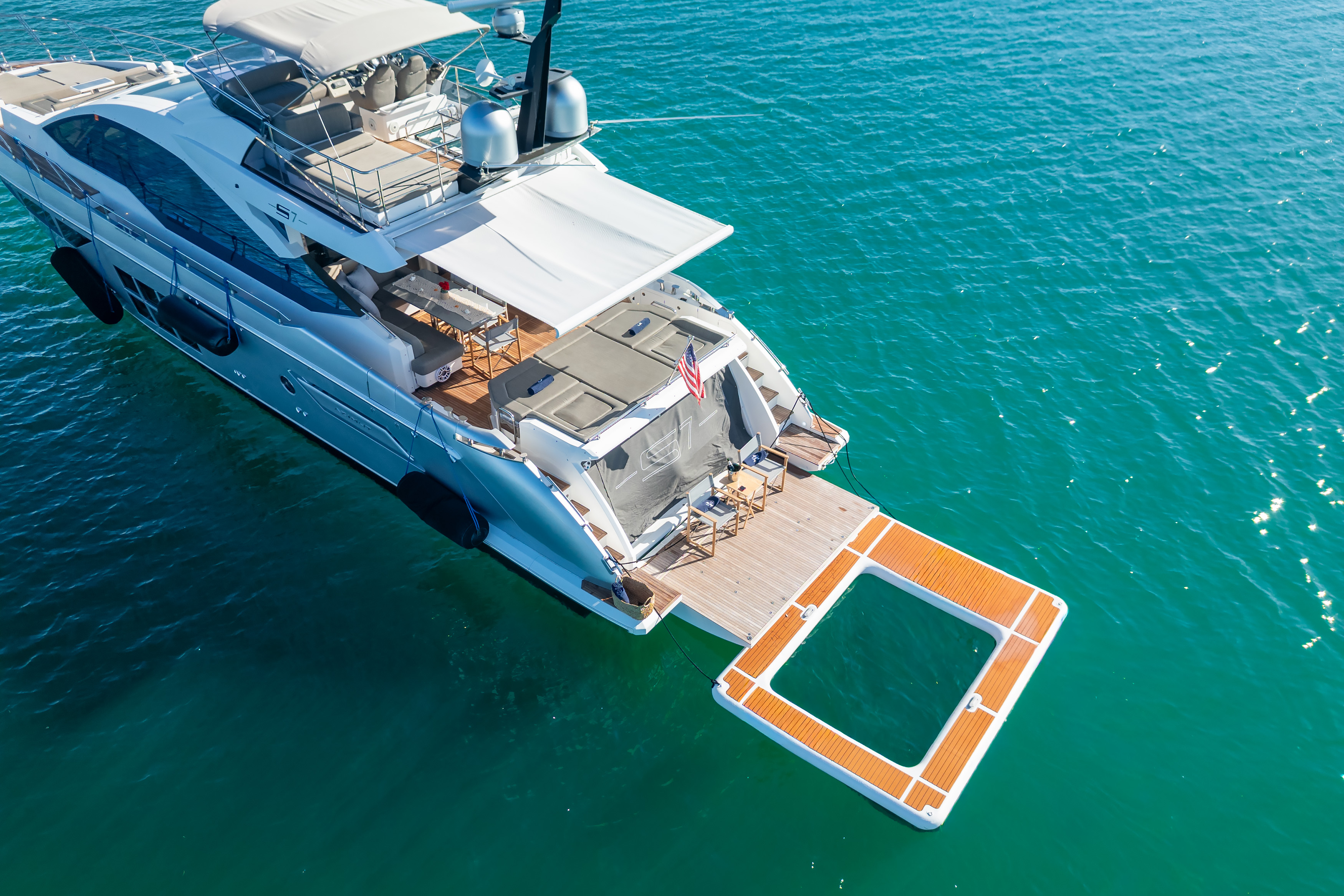 Yacht with tender deployed in turquoise water